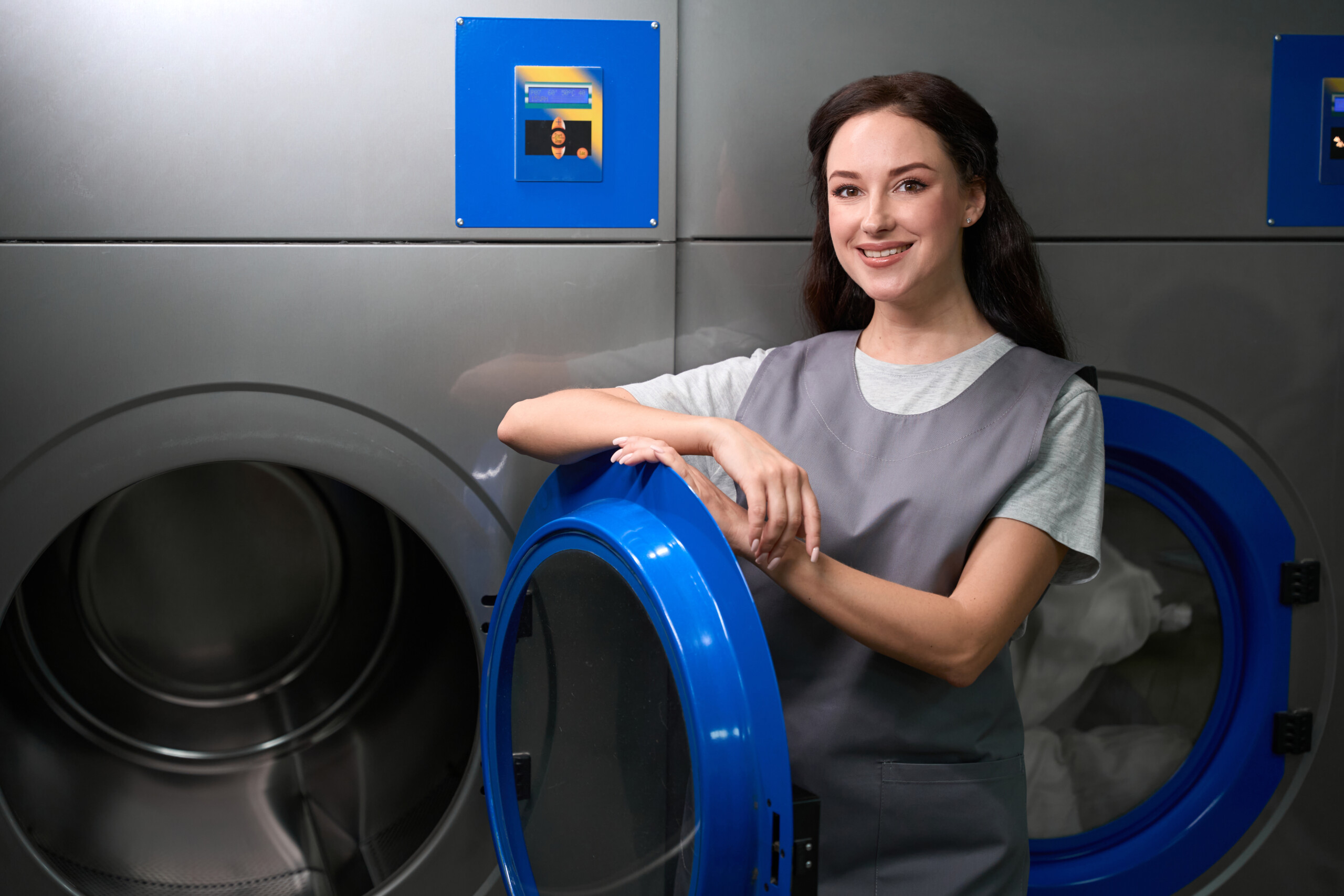 Woman dry-cleaning service worker standing near big industrial machine